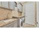 Well-appointed laundry room with granite counters, stone backsplash, cabinetry, and a front load washer and dryer at 6211 Legends Blvd, Bradenton, FL 34210