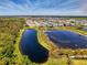 Aerial view of a house on a pond with neighborhood in the background and ample landscaping at 9487 Tequila Sunrise Dr, Sarasota, FL 34241