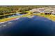 Aerial view showcasing a large pond with a house and pool in the background, surrounded by trees at 9487 Tequila Sunrise Dr, Sarasota, FL 34241