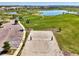 Community aerial view showcasing a sand volleyball court, open green spaces, a serene lake, and parking area at 9487 Tequila Sunrise Dr, Sarasota, FL 34241