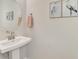 The bathroom has a pedestal sink with a towel rack and framed artwork hanging above the toilet at 9487 Tequila Sunrise Dr, Sarasota, FL 34241