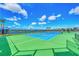 Brightly colored tennis court ready for play under a clear, sunny sky, surrounded by lush greenery and fencing at 9487 Tequila Sunrise Dr, Sarasota, FL 34241