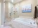 Elegant bathroom featuring a soaking tub, a separate glass shower, and tiled walls at 12518 Harbour Landings Dr, Cortez, FL 34215
