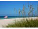 Seaside vista featuring a striped beach umbrella on white sand under a clear blue sky at 12518 Harbour Landings Dr, Cortez, FL 34215