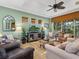 Comfortable living room with a ceiling fan, entertainment center, and a view of the screened porch at 12518 Harbour Landings Dr, Cortez, FL 34215