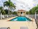 Beautiful swimming pool with lounge chairs surrounded by tropical landscaping and white picket fence at 12518 Harbour Landings Dr, Cortez, FL 34215