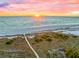 Scenic beach view features a pristine sandy shoreline, calm blue waters, and a vibrant sunset sky at 141 Avenida Veneccia, Sarasota, FL 34242