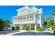 Stunning three-story beach house with a white exterior, multiple balconies, and well-maintained landscaping at 141 Avenida Veneccia, Sarasota, FL 34242