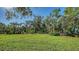 Lush backyard with mature trees and greenery, leading to a charming residence at 1440 Kimlira Ln, Sarasota, FL 34231
