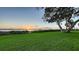 Serene waterfront backyard featuring mature trees, a well-maintained lawn, and a beautiful sunset at 1440 Kimlira Ln, Sarasota, FL 34231