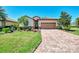 Charming single-story home with a well-manicured lawn, stone accents, and a brick driveway at 167 Wandering Wetlands Cir, Bradenton, FL 34212