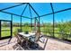 Enclosed patio featuring a dining set, umbrella, and serene views of the lush backyard at 167 Wandering Wetlands Cir, Bradenton, FL 34212