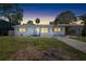 Charming single-story home with a carport and a well-manicured lawn under a beautiful dusk sky at 1827 Nevada Ne Ave, St Petersburg, FL 33703