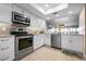 Modern kitchen features stainless steel appliances, white cabinets, stone countertops and plank flooring at 1900 Cove Ii Pl # 133, Sarasota, FL 34242