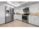 Modern kitchen features stainless steel appliances, white cabinets, stone countertops and plank flooring at 1900 Cove Ii Pl # 133, Sarasota, FL 34242