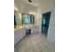 Bright bathroom featuring dual sinks, a large mirror, and a tile floor at 2097 Wasatch Dr, Sarasota, FL 34235