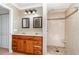 Tiled bathroom with dual sinks, wood cabinets, and walk-in shower at 26506 Copiapo Cir, Punta Gorda, FL 33983