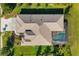 Bird's-eye view of a tan home with a brown roof, an outdoor screened-in pool, and a well-manicured lawn at 391 Snapdragon Loop, Bradenton, FL 34212