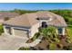 Aerial view of a tan, single story home with well maintained landscaping, a three car garage and a brown roof at 391 Snapdragon Loop, Bradenton, FL 34212