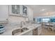 Open concept kitchen with stainless steel sink and white cabinetry flowing into a dining area and ocean view living room at 420 Beach Rd # 502, Sarasota, FL 34242