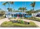 Charming blue single story home boasts lush landscaping, brick driveway, and a vibrant red front door at 502 69Th St, Holmes Beach, FL 34217