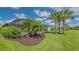 Lush backyard featuring a screened lanai, palm trees, and manicured landscaping at 5562 Rain Lily Ct, Sarasota, FL 34238