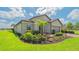 Beautifully landscaped front yard with a well-maintained lawn, palm tree, and colorful flowerbeds at 5562 Rain Lily Ct, Sarasota, FL 34238