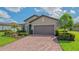 View of the home's garage with a brick driveway, and manicured lawn in a well-maintained community at 5562 Rain Lily Ct, Sarasota, FL 34238