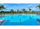 Resort-style pool with palm trees, lounge chairs, and umbrellas under a blue, cloudy sky at 5562 Rain Lily Ct, Sarasota, FL 34238