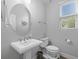 Powder room featuring gray walls, white fixtures, a round mirror, vanity, and a window providing natural light at 5954 Anise Dr, Sarasota, FL 34238