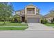 Two-story tan home with a two-car garage, front porch, second story balcony, and manicured lawn at 5954 Anise Dr, Sarasota, FL 34238