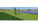 Green backyard featuring beautiful lake views, lush green lawn, and a young tree at 6105 114Th E Dr, Parrish, FL 34219
