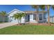Charming single-story home with blue exterior, well-manicured lawn, and palm trees. Garage at 6105 114Th E Dr, Parrish, FL 34219