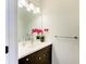 Half bathroom featuring a white quartz countertop and dark brown cabinets, accented with a vibrant red orchid at 10614 Morning Marsh Ln, Parrish, FL 34219