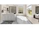 Bright bathroom featuring dual vanities, soaking tub under window and glass shower at 12352 Auburndale Ct, Venice, FL 34293