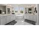 Bright bathroom featuring dual vanities, soaking tub under window with marble floors at 12352 Auburndale Ct, Venice, FL 34293