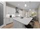 White kitchen with stainless steel range hood, modern countertops, island with bar seating, and recessed lighting at 12352 Auburndale Ct, Venice, FL 34293