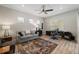 Cozy living room featuring a comfortable gray couch, modern ceiling fan, and a dedicated workspace with desk and chair at 12352 Auburndale Ct, Venice, FL 34293