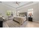 Spacious main bedroom with a king bed, tray ceiling, and a sitting area by the window at 12352 Auburndale Ct, Venice, FL 34293