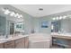 Bathroom with double sinks, a soaking tub, decorative mirrors, and stylish light fixtures at 1260 Dolphin Bay Way # 404, Sarasota, FL 34242