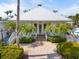 Inviting clubhouse entrance with brick walkway, lush landscaping, and charming architectural details at 1260 Dolphin Bay Way # 404, Sarasota, FL 34242
