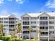 Exterior view of condo featuring multiple screened patios overlooking manicured lawn and palm tree landscape at 1260 Dolphin Bay Way # 404, Sarasota, FL 34242