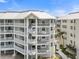 Condominium complex featuring white balconies and stairs, complemented by lush landscaping and a sunny sky at 1260 Dolphin Bay Way # 404, Sarasota, FL 34242