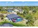 Aerial view of a home with a screened pool, patio, and lush landscaping in a quiet neighborhood at 145 Baytree Dr, Rotonda West, FL 33947