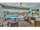 Cozy covered outdoor patio with comfortable seating, ceiling fan, and views of the screened-in pool area at 145 Baytree Dr, Rotonda West, FL 33947