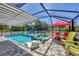 Inviting screened-in pool area with a striped awning, lounge chairs, and lush greenery at 145 Baytree Dr, Rotonda West, FL 33947