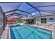 Relaxing backyard featuring a large screened-in pool, spa, and covered patio with comfortable seating area at 145 Baytree Dr, Rotonda West, FL 33947