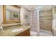 Well-lit bathroom featuring granite vanity, a tiled shower with a decorative curtain, and modern fixtures at 1610 Treehouse Cir # T130, Sarasota, FL 34231