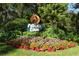 Community entrance sign 'Pelican Cove' amidst lush greenery and colorful flowers, creating a welcoming atmosphere at 1610 Treehouse Cir # T130, Sarasota, FL 34231