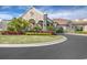 Exterior view of a clubhouse, featuring a well-manicured lawn, a paved driveway, and detailed stonework at 17604 Hickok Belt Loop, Bradenton, FL 34211